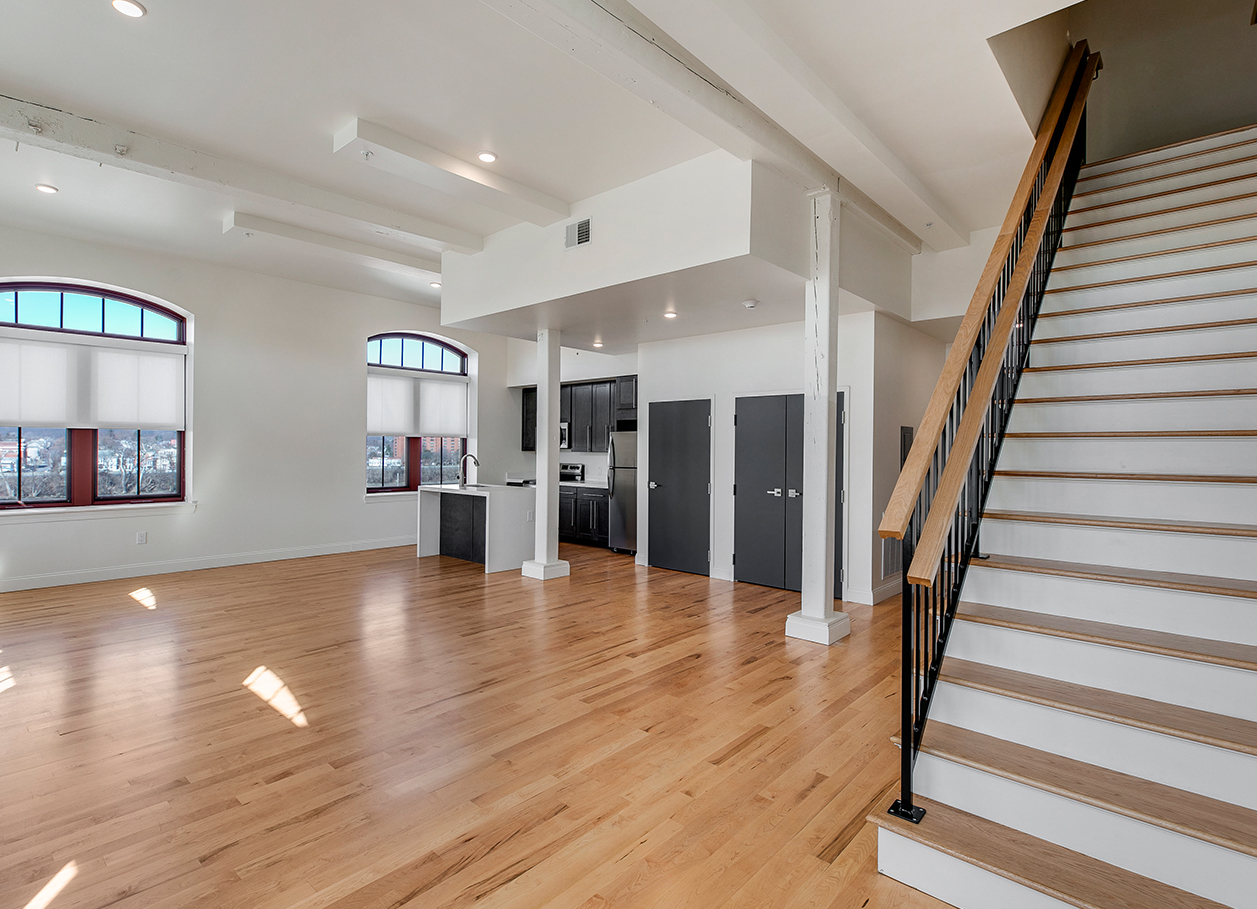 Photo of an empty living area and the stairs to the second floor of an apartment at 2 River Street.