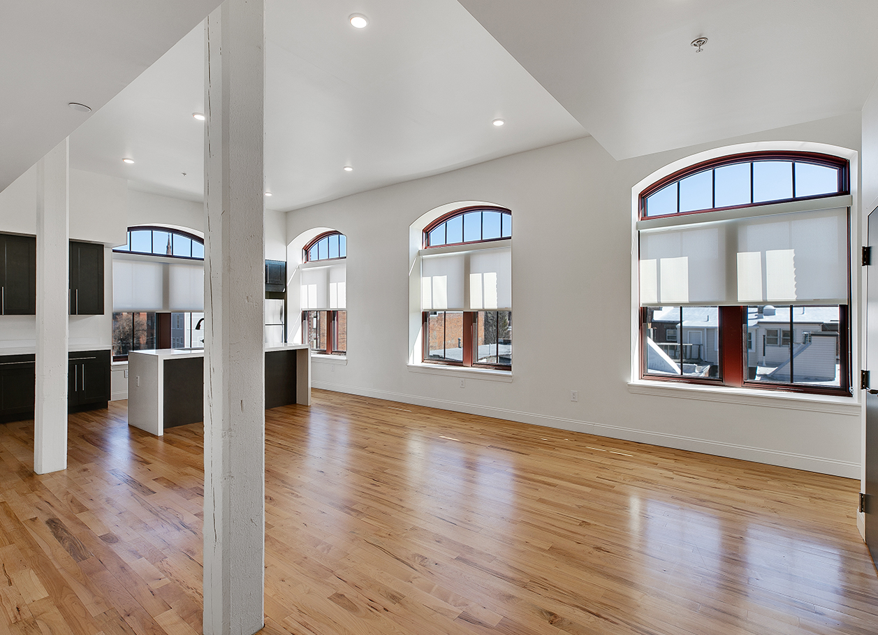 Photo of an empty living area looking back toward kitchen in an apartment at 2 River Street.