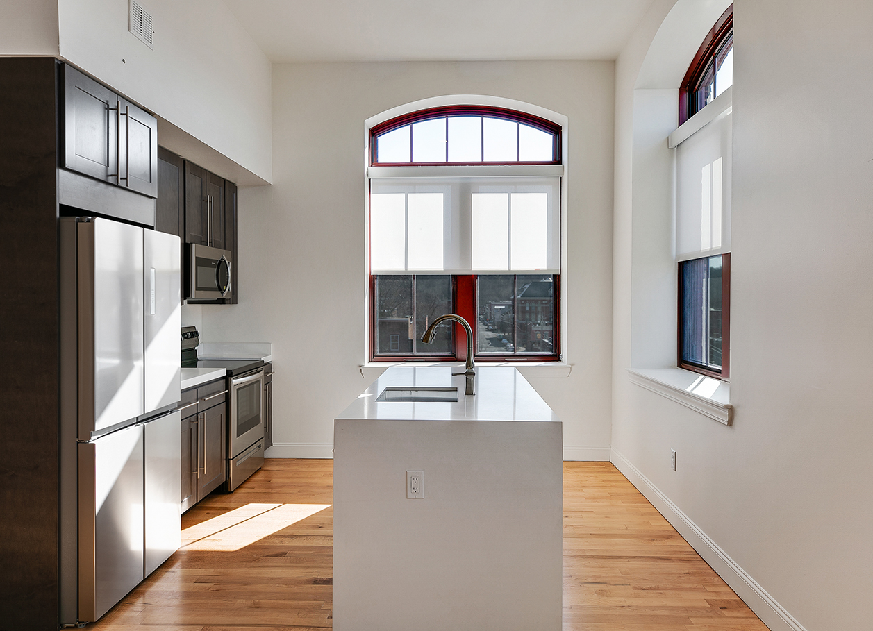 Photo looking between the sink and cooking area counters of a kitchen in an apartment at 2 River Street.